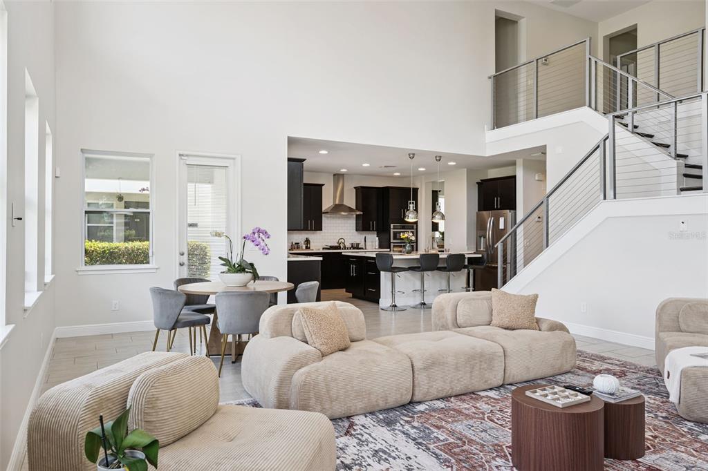 An open-concept living area features a modern kitchen, dining space, and a staircase with railings — 7211 STILL POND LANE, WINDERMERE, FL