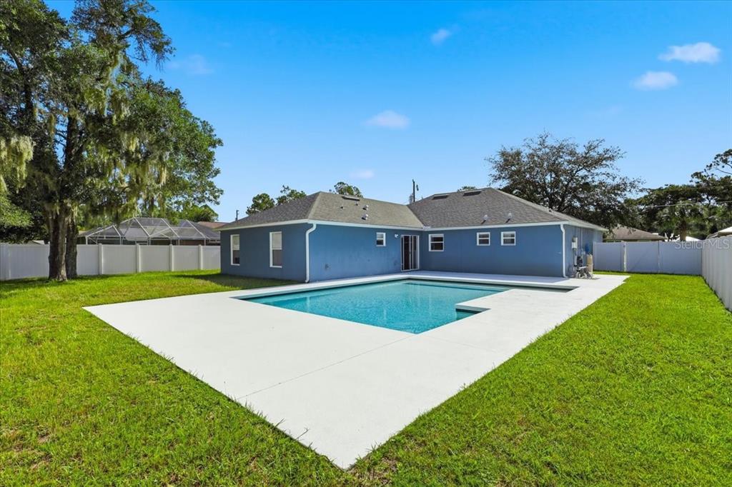 The exterior of a blue house features a swimming pool and a white fence — 41 ZEPHYR LILY TRAIL, PALM COAST, FL