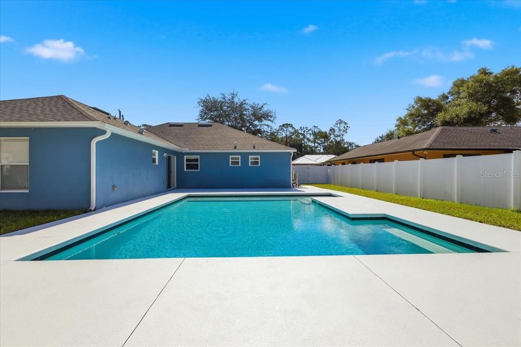 A blue house with a swimming pool and a white fence in the backyard — 41 ZEPHYR LILY TRAIL, PALM COAST, FL