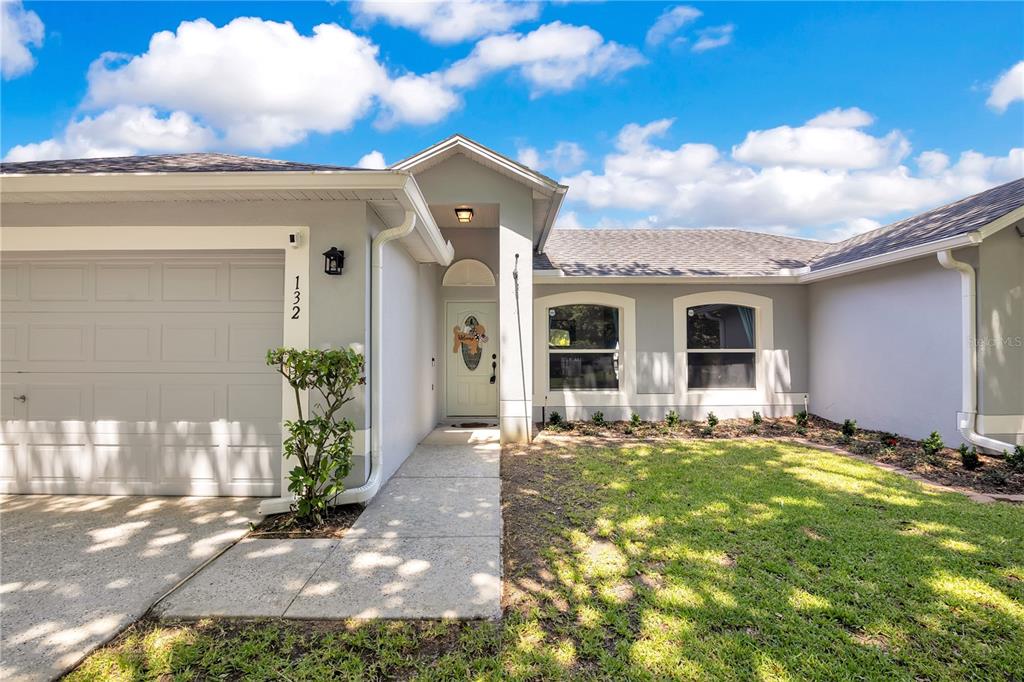 A single-story gray house with a two-car garage and a large tree in the yard — 132 ZACHARY WADE STREET, WINTER GARDEN, FL