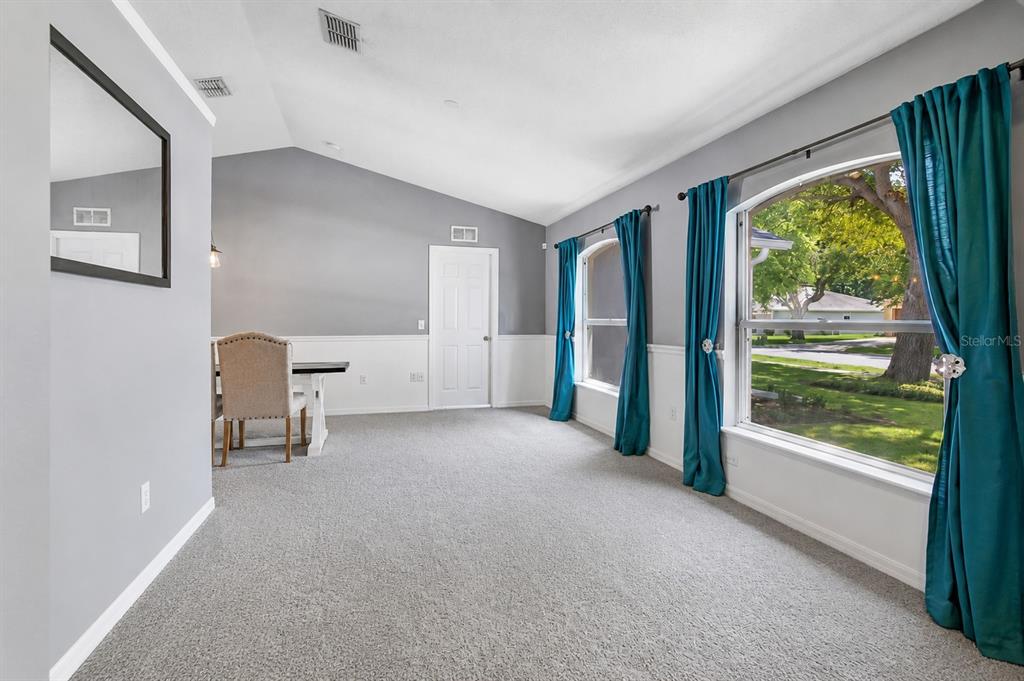 A dining area with carpeted floors, a vaulted ceiling, and an arched entryway to the kitchen — 132 ZACHARY WADE STREET, WINTER GARDEN, FL