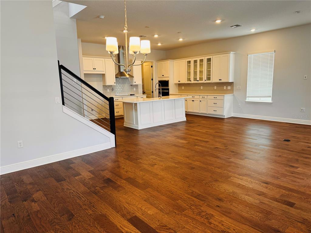 A kitchen with white cabinetry, a central island, and hardwood floors next to a staircase — 10120 PEEBLES STREET, ORLANDO, FL