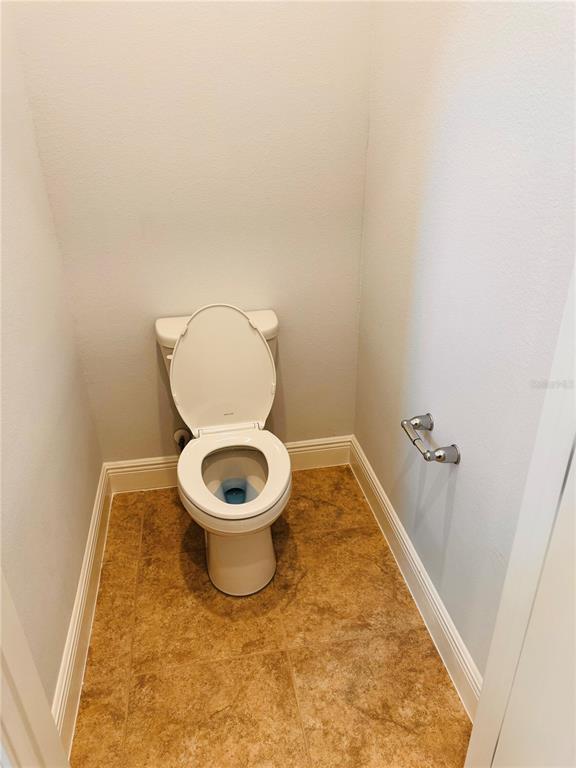 A small bathroom with a white toilet and tan tile flooring — 10120 PEEBLES STREET, ORLANDO, FL
