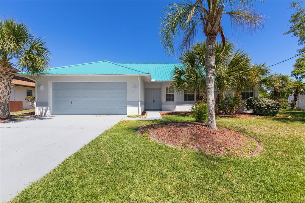 A single-story house with a teal metal roof, white stucco exterior, and a two-car garage — 21 CRESCENT COURT S, PALM COAST, FL