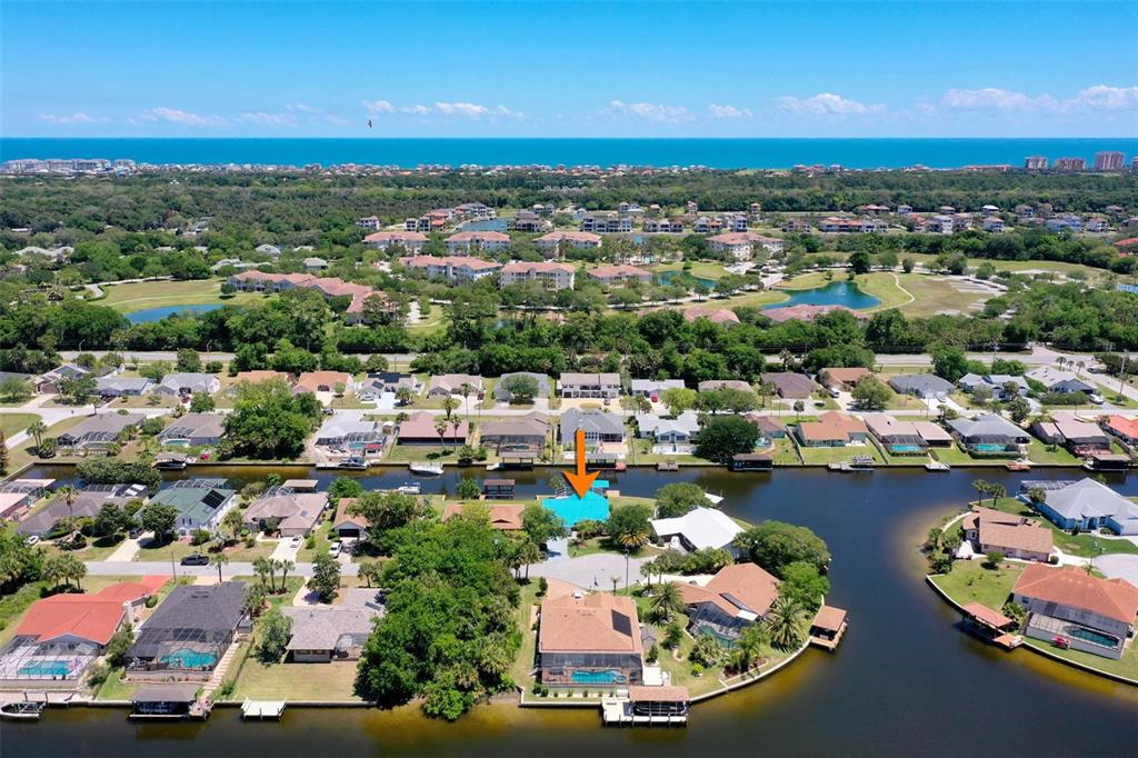 An aerial view shows a waterfront house with a pool and a dock on a canal — 21 CRESCENT COURT S, PALM COAST, FL