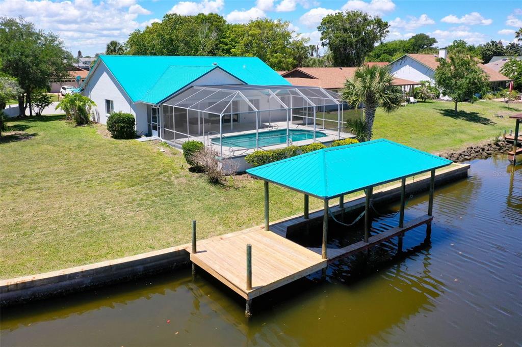 An aerial view of a waterfront house with a teal metal roof, pool, and dock — 21 CRESCENT COURT S, PALM COAST, FL