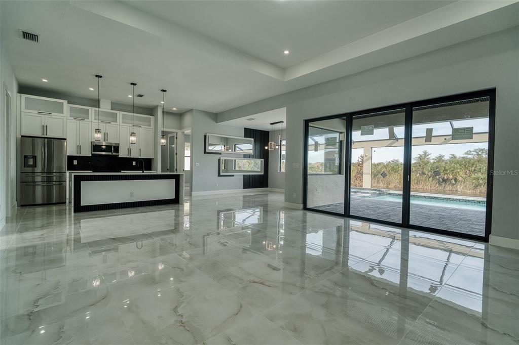 A modern kitchen and living area with white marble floors and large sliding glass doors — 10474 WINNIPEG STREET, PORT CHARLOTTE, FL