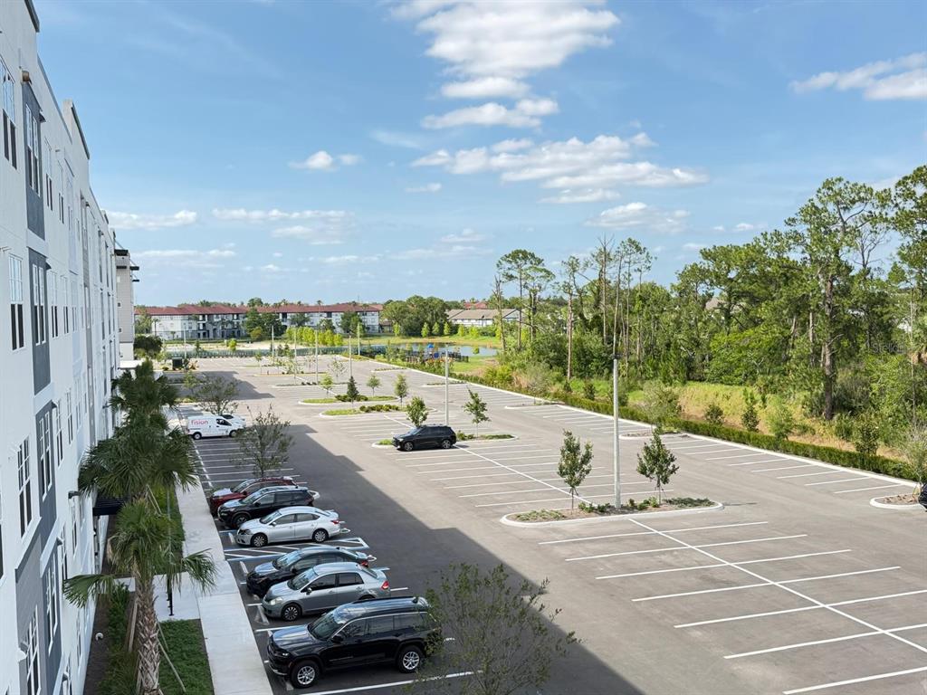 An elevated view of a large parking lot next to a modern apartment building — 5587 MILLENIA PARK BLVD UNIT 418, ORLANDO, FL