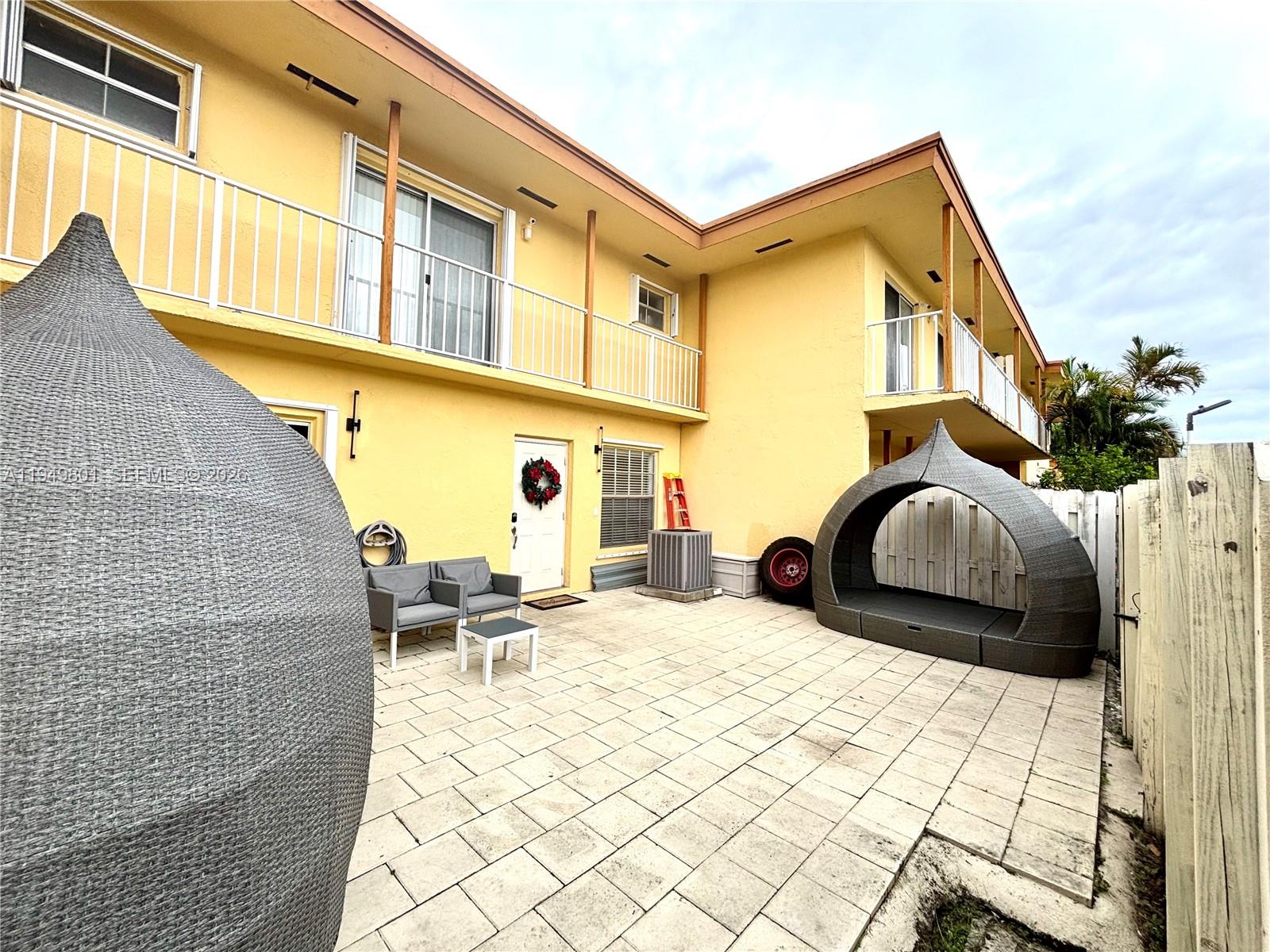 A yellow two-story building features a paved patio with outdoor furniture and a privacy fence — 8384 SW 154th Ave # 68, Miami FL 33193, MIAMI, FL