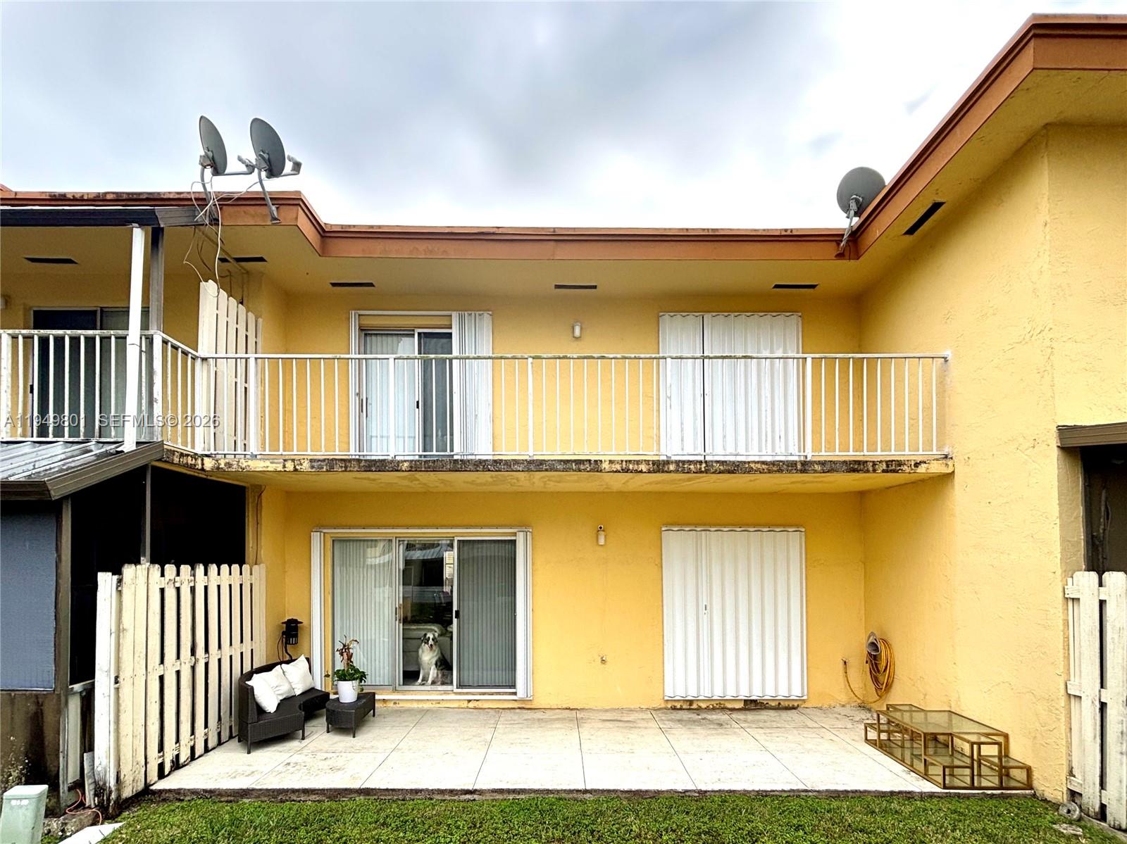 A two-story yellow building features a ground-level patio and an upper-level balcony with railings — 8384 SW 154th Ave # 68, Miami FL 33193, MIAMI, FL