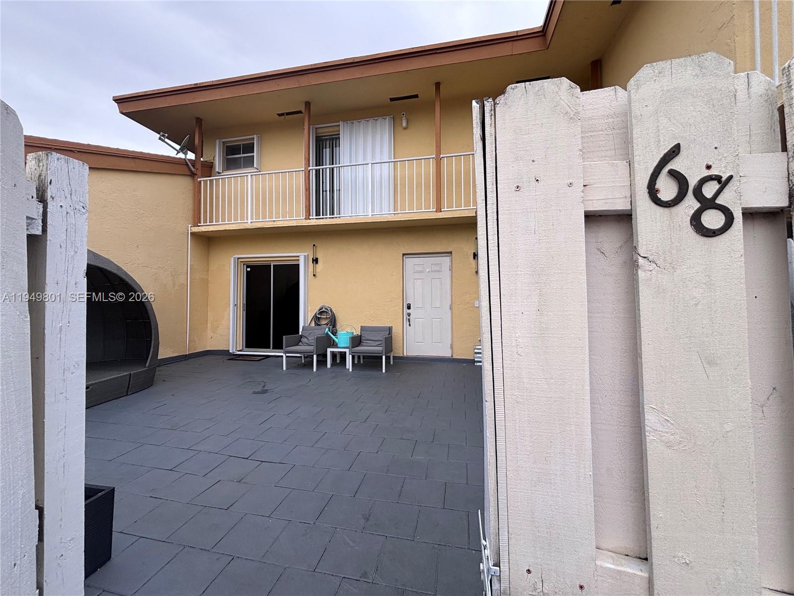 A patio with dark tiles, two chairs, and a small table sits before a building — 8384 SW 154th Ave # 68, Miami FL 33193, MIAMI, FL
