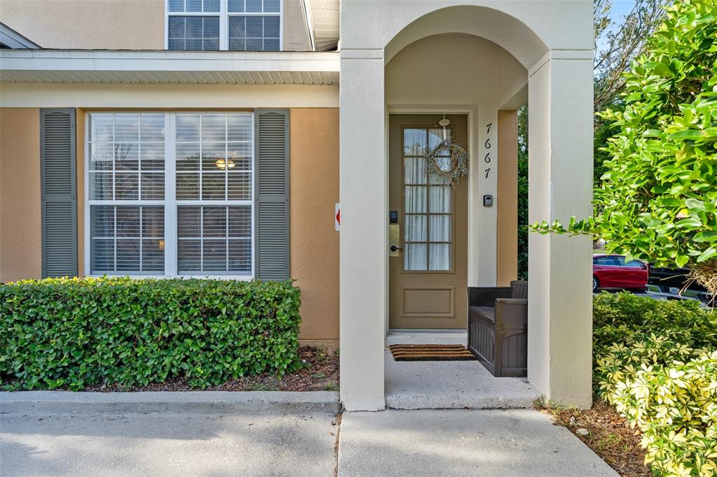 The exterior of a tan house features a front door with a wreath and shutters — 7667 OTTERSPOOL STREET, KISSIMMEE, FL