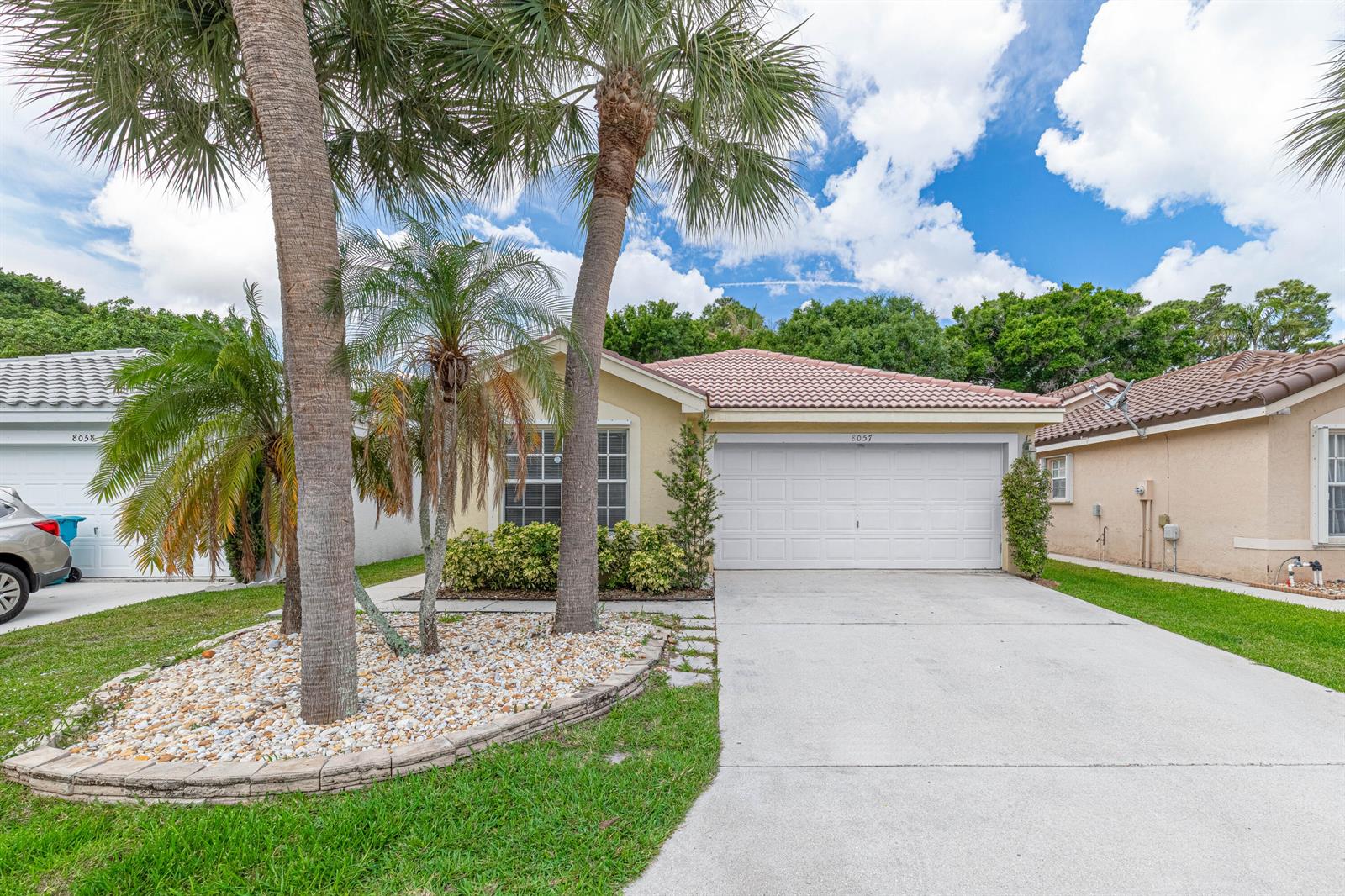 A single-story house with a white garage door, palm trees, and a concrete driveway — 8057 Stirrup Cay Court, Boynton Beach FL 33436, BOYNTON BEACH, FL