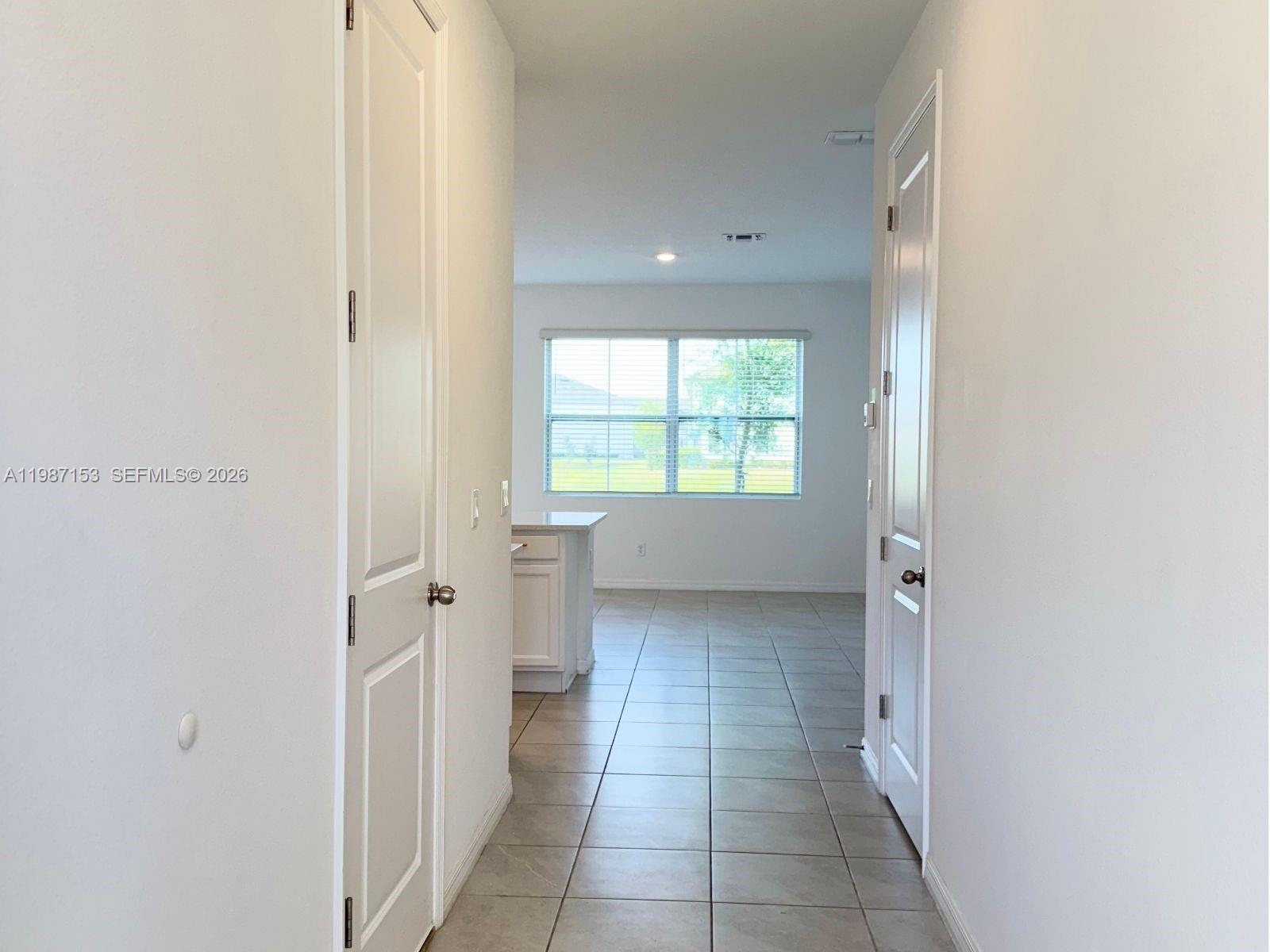 A tiled hallway leads to an open kitchen and living area with a large window — 1613 PELICAN DRIVE, Davenport FL 33896, DAVENPORT, FL