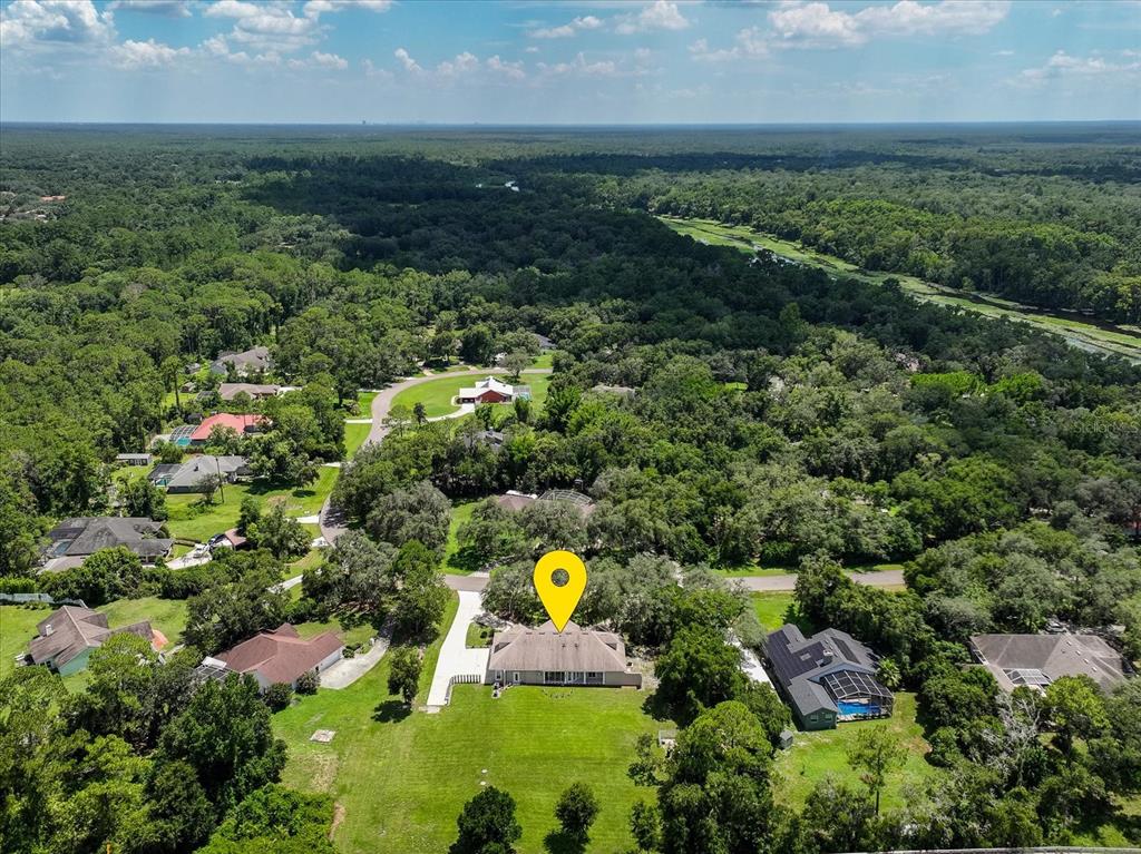 An aerial view shows a single-story house with a large backyard surrounded by dense trees — 180 RIVER OAKS CIRCLE, SANFORD, FL