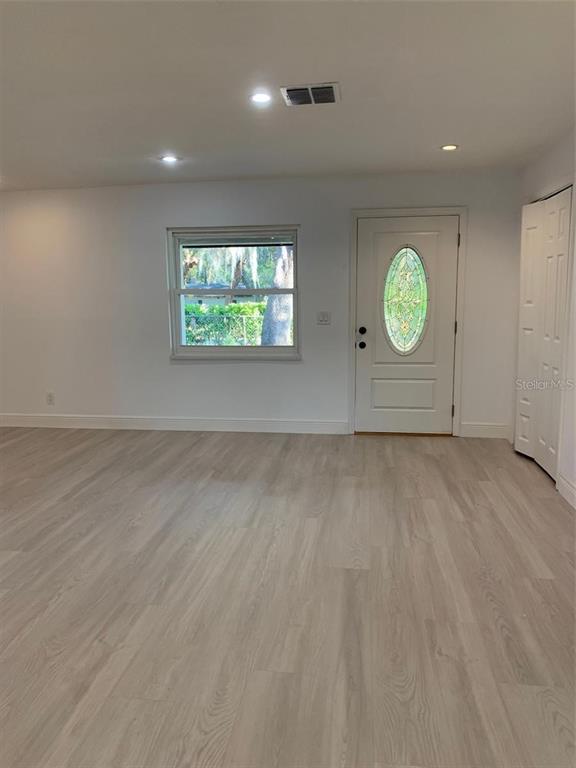 A living room features light wood-look flooring, a white front door, and a single window — 183 E GRAND BEND AVENUE, LAKE MARY, FL