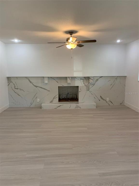 A room features light wood-look flooring, a ceiling fan, and a marble-tiled fireplace wall — 183 E GRAND BEND AVENUE, LAKE MARY, FL