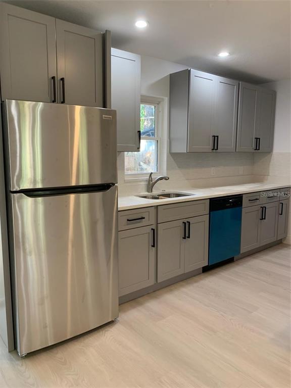 A kitchen features gray cabinets, stainless steel appliances, a window, and light-colored wood flooring — 183 E GRAND BEND AVENUE, LAKE MARY, FL