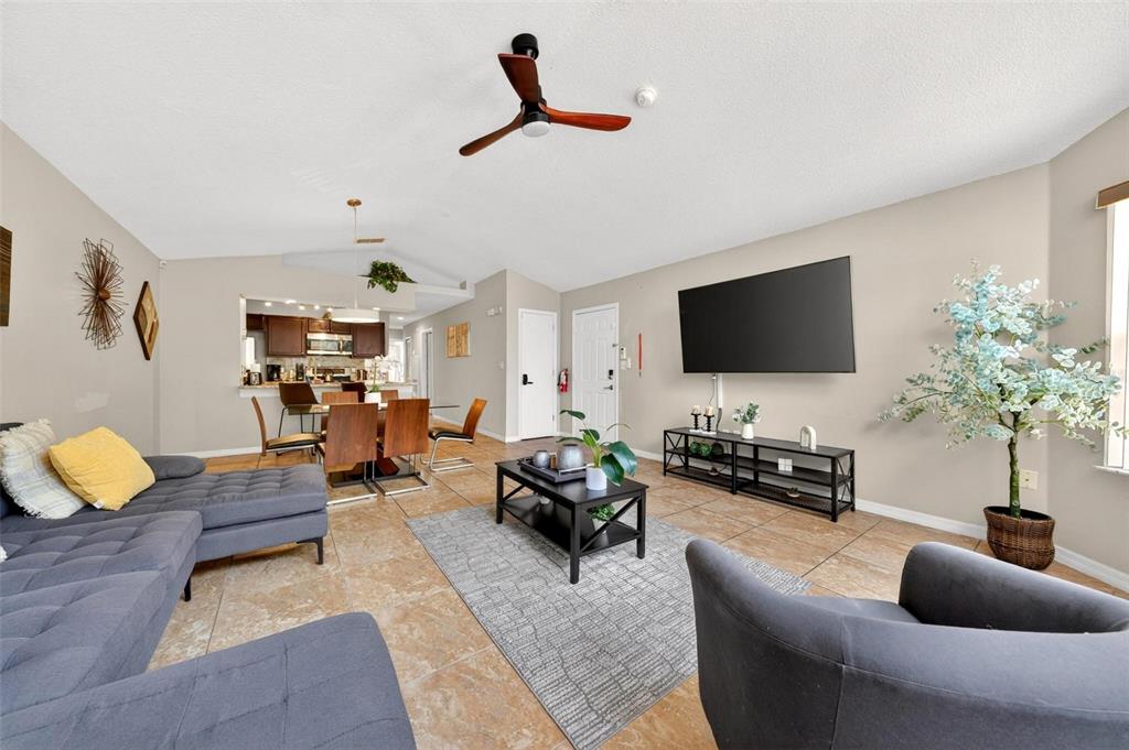 A living room features a grey sectional sofa, a coffee table, and an open kitchen — 8718 RAIN FOREST PLACE UNIT C, KISSIMMEE, FL