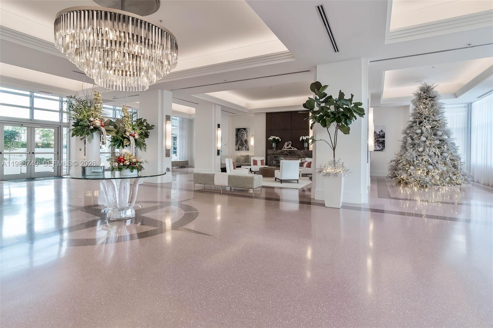 A spacious, modern lobby features a large crystal chandelier, polished floors, and a Christmas tree — 3737 Collins Ave # 203, Miami Beach FL 33140, MIAMI BEACH, FL