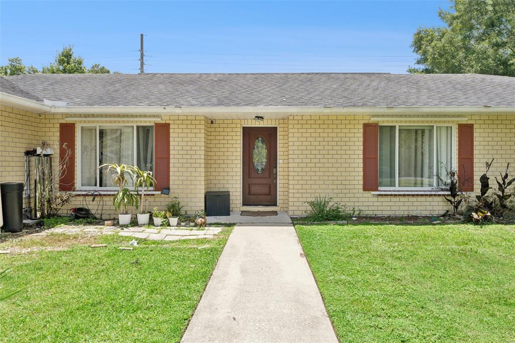 A single-story brick house features a central front door, two windows with shutters, and a walkway — 1756 TANGLEWOOD DRIVE, KISSIMMEE, FL