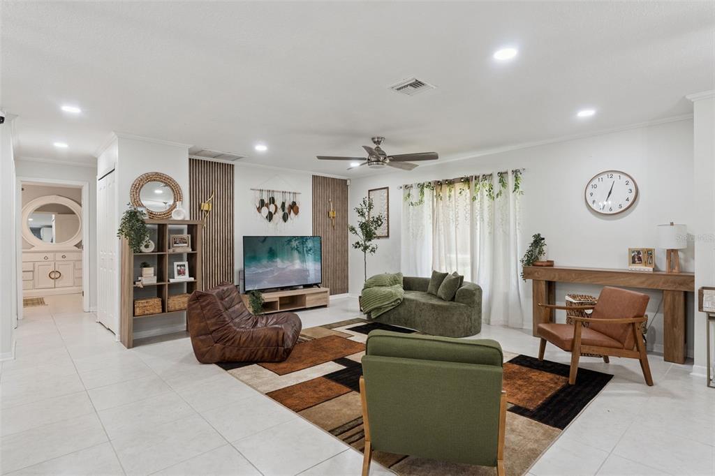 A living room features a geometric area rug, a television, and various seating options — 1756 TANGLEWOOD DRIVE, KISSIMMEE, FL