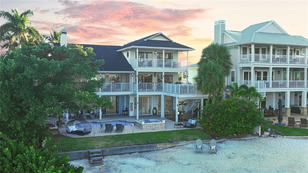 A yellow two-story house features a white front door, stairs, and a paved driveway — 255 46TH AVENUE, ST PETE BEACH, FL