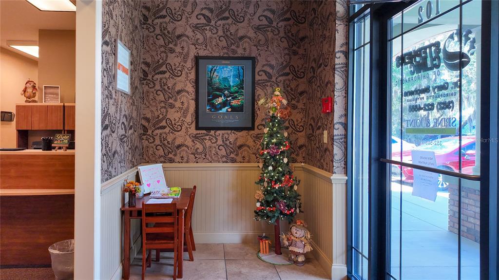 A small waiting area features paisley wallpaper, a wooden table, and a decorated Christmas tree — 3235 SW 34TH STREET UNIT 102, OCALA, FL