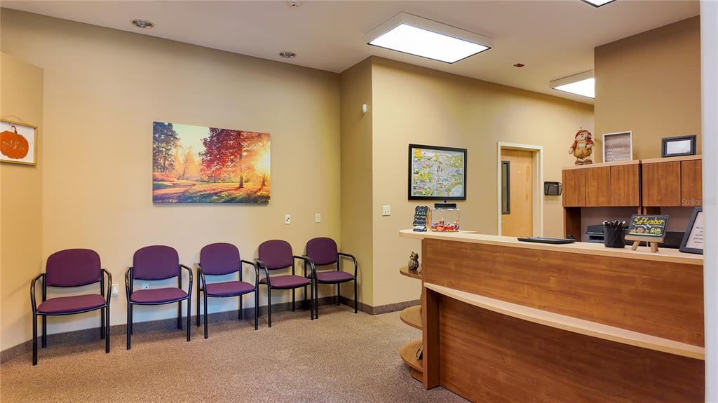 A waiting room features five purple chairs, a wooden reception desk, and a landscape painting — 3235 SW 34TH STREET UNIT 102, OCALA, FL