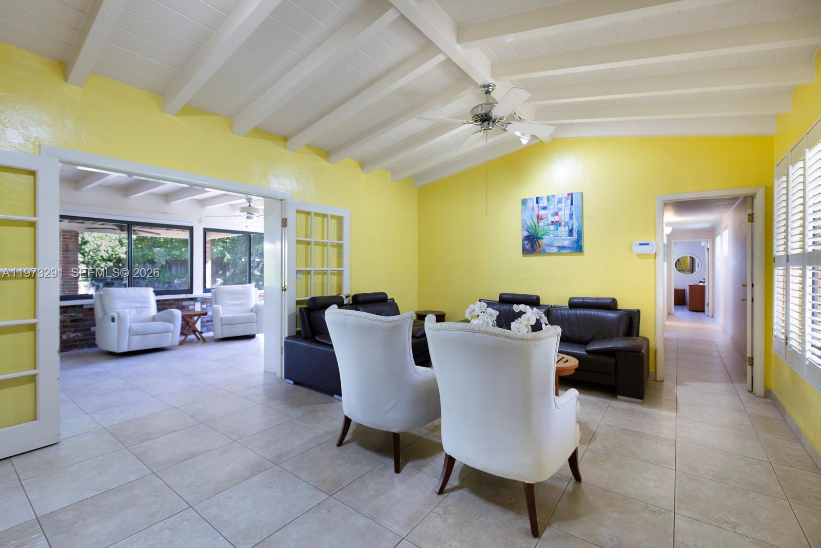 A living room features yellow walls, a vaulted beamed ceiling, tile floors, and white furniture — 3721 SW 58th Ave, Miami FL 33155, MIAMI, FL