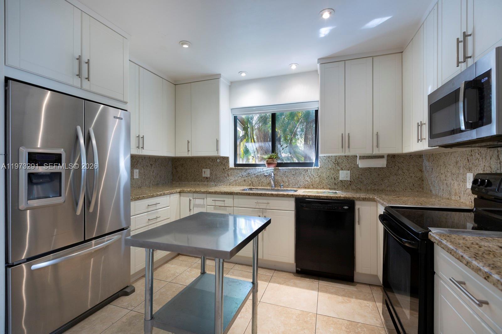 A kitchen features white cabinets, stainless steel appliances, granite countertops, and a metal island — 3721 SW 58th Ave, Miami FL 33155, MIAMI, FL