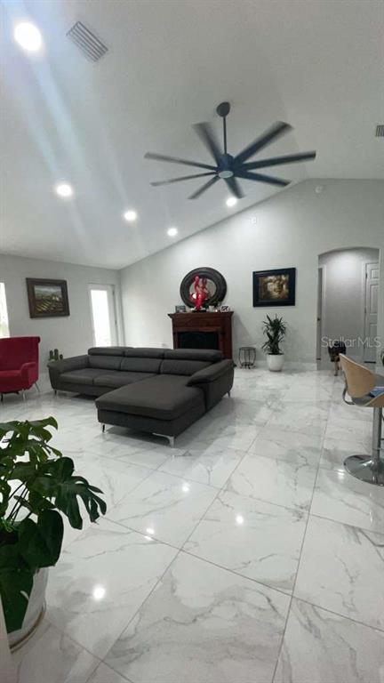 A living room features a large gray sectional sofa, white marble floors, and a ceiling fan — 5715 SW 128TH PLACE, OCALA, FL