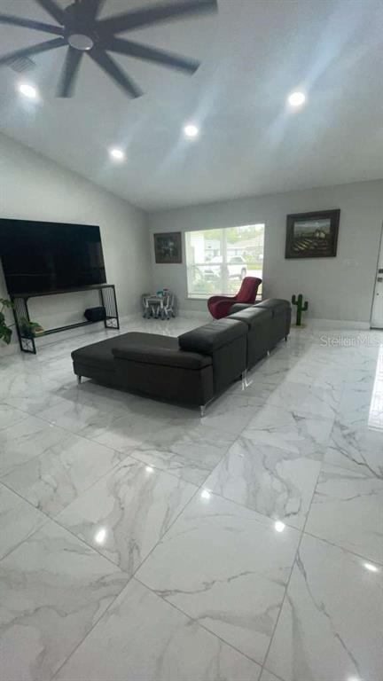 A living room features a large dark sectional sofa, a television on a stand, and tile flooring — 5715 SW 128TH PLACE, OCALA, FL