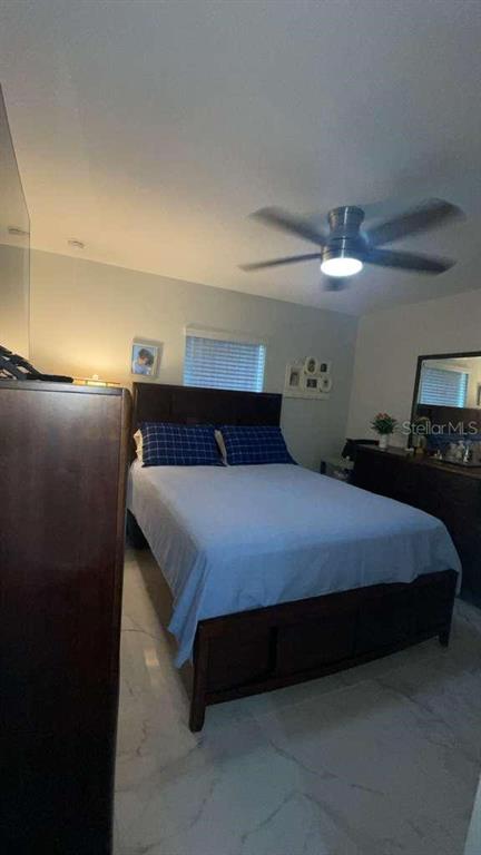 A bedroom features a dark wood bed frame, light blue bedding, and a ceiling fan — 5715 SW 128TH PLACE, OCALA, FL