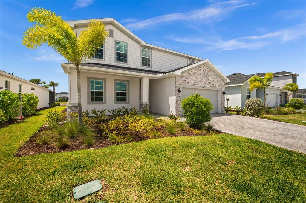 A two-story suburban house with white siding, a stone facade, and a paved driveway — 15021 ANCHORAGE ROAD, PUNTA GORDA, FL
