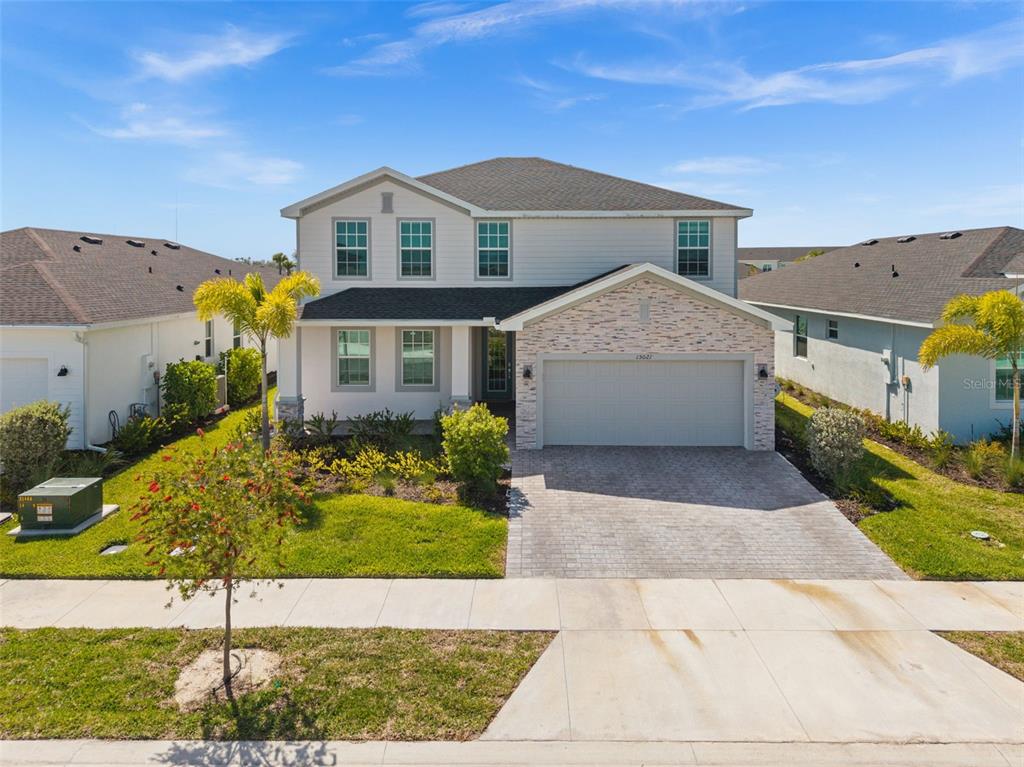 A two-story suburban house features a stone-accented garage, light siding, and a paved driveway — 15021 ANCHORAGE ROAD, PUNTA GORDA, FL