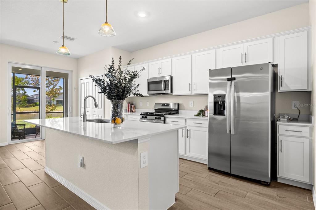 A modern kitchen features white cabinets, stainless steel appliances, a large island, and tile flooring — 15021 ANCHORAGE ROAD, PUNTA GORDA, FL