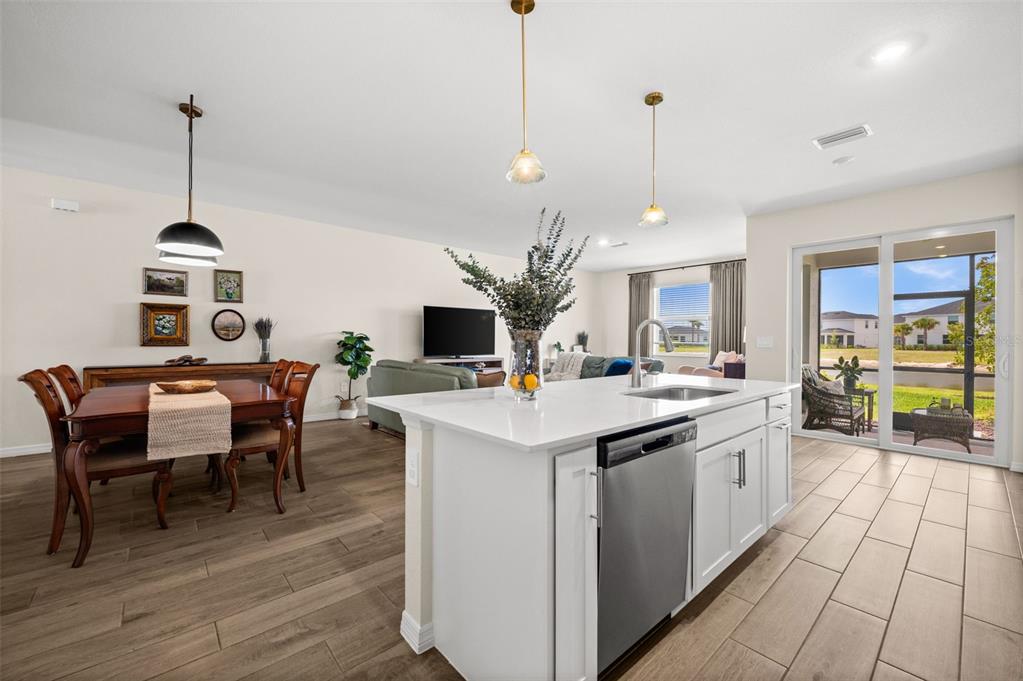 A kitchen island with a stainless steel dishwasher faces a dining area and living room — 15021 ANCHORAGE ROAD, PUNTA GORDA, FL