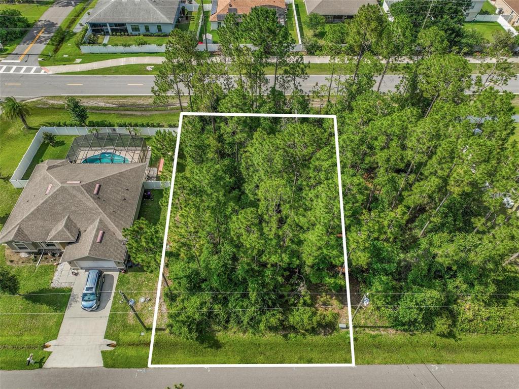 An aerial view shows a rectangular, tree-covered vacant lot situated between a house and woods — 3 KATHRYN PLACE, PALM COAST, FL