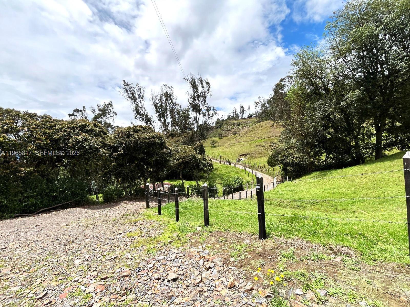 A gravel driveway leads past a wire fence toward a grassy hill with trees — Palenque 1 E Gama Cundinamarca, Vereda Palenque 1, 2512247, FL