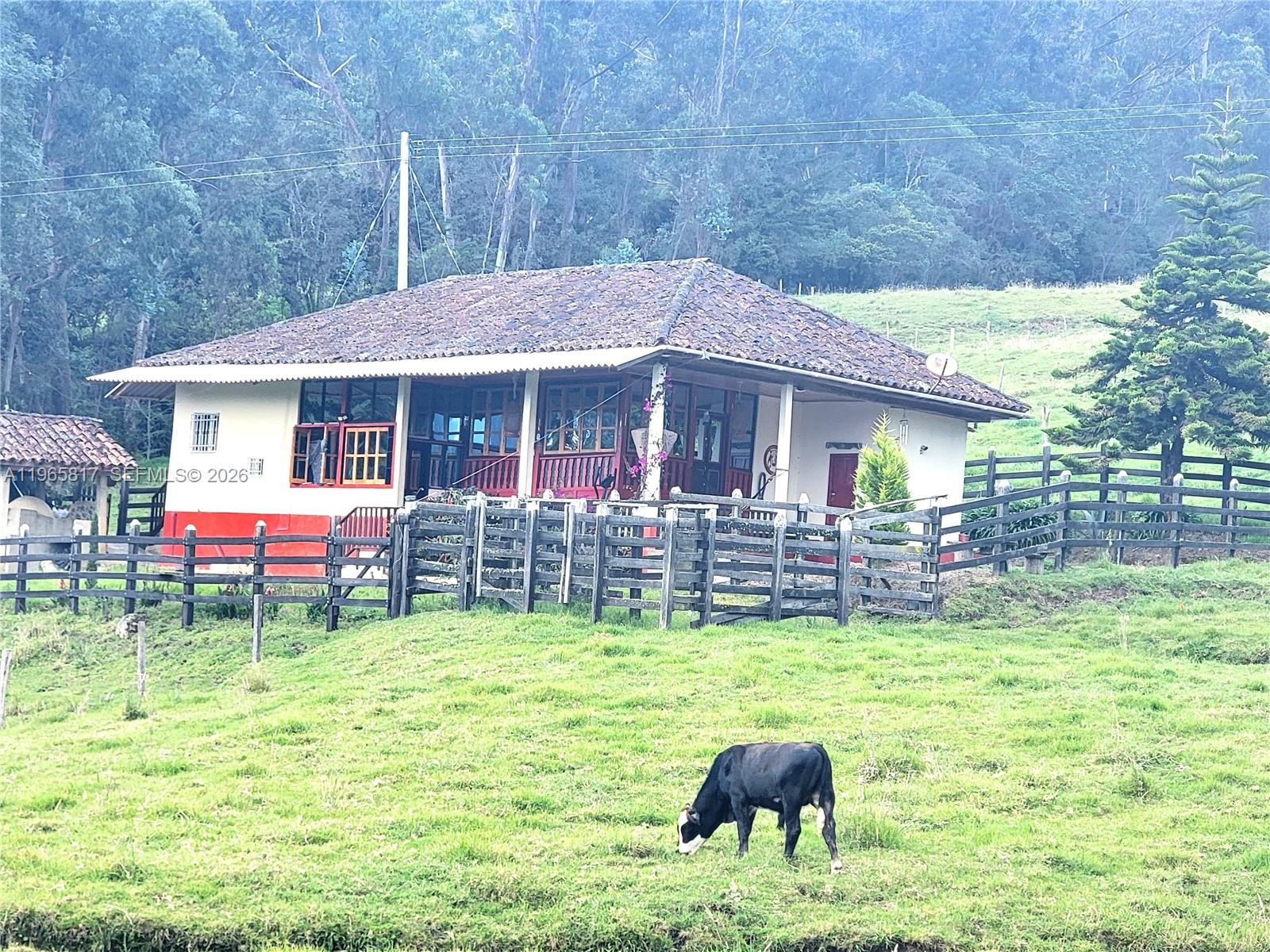 A single-story house with a tiled roof sits behind a wooden fence in a pasture — Palenque 1 E Gama Cundinamarca, Vereda Palenque 1, 2512247, FL
