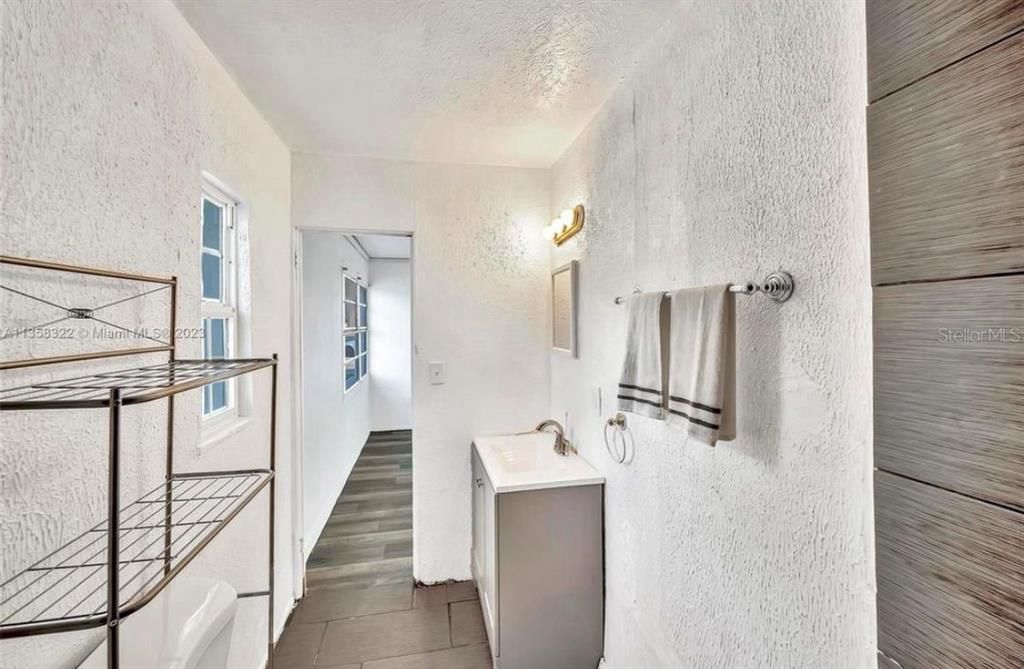 A bathroom features a white vanity, a metal shelving unit, and a towel rack — 1001 N 16TH COURT, FORT PIERCE, FL