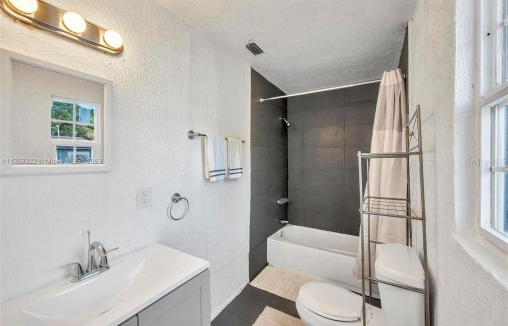 A bathroom features a gray vanity, a white toilet, and a tub with dark tiles — 1001 N 16TH COURT, FORT PIERCE, FL
