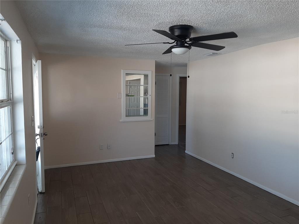 A living room features wood-look tile flooring, a ceiling fan, and an interior pass-through window — 4808 SALEM DRIVE, NEW PORT RICHEY, FL