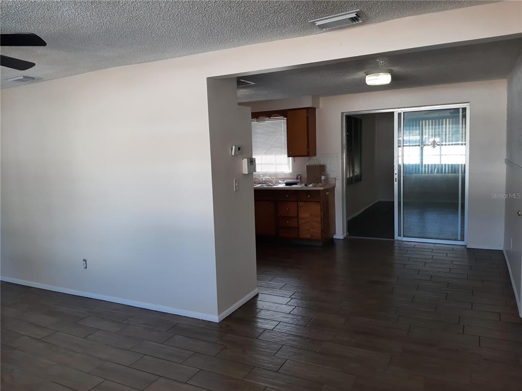 A view of a living area with tile floors leading into a kitchen and patio — 4808 SALEM DRIVE, NEW PORT RICHEY, FL