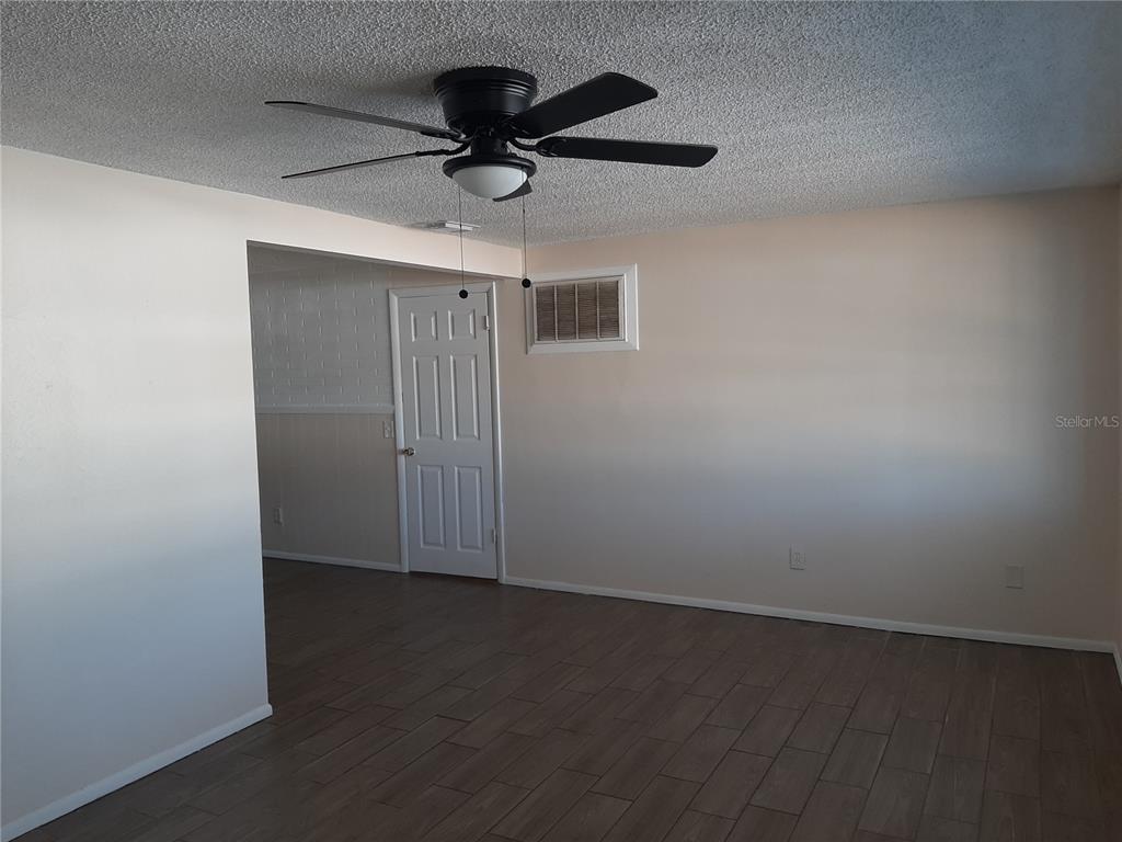 A room with wood-look tile flooring, a ceiling fan, and a white interior door — 4808 SALEM DRIVE, NEW PORT RICHEY, FL