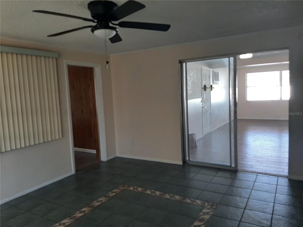 A room with dark tile flooring, a ceiling fan, and a sliding glass door — 4808 SALEM DRIVE, NEW PORT RICHEY, FL