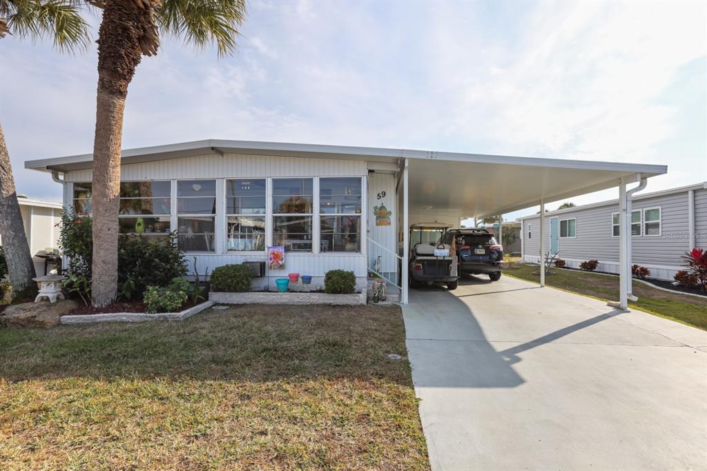 A single-story mobile home with a carport, a golf cart, and a parked SUV — 2100 KINGS HIGHWAY UNIT 59, PORT CHARLOTTE, FL