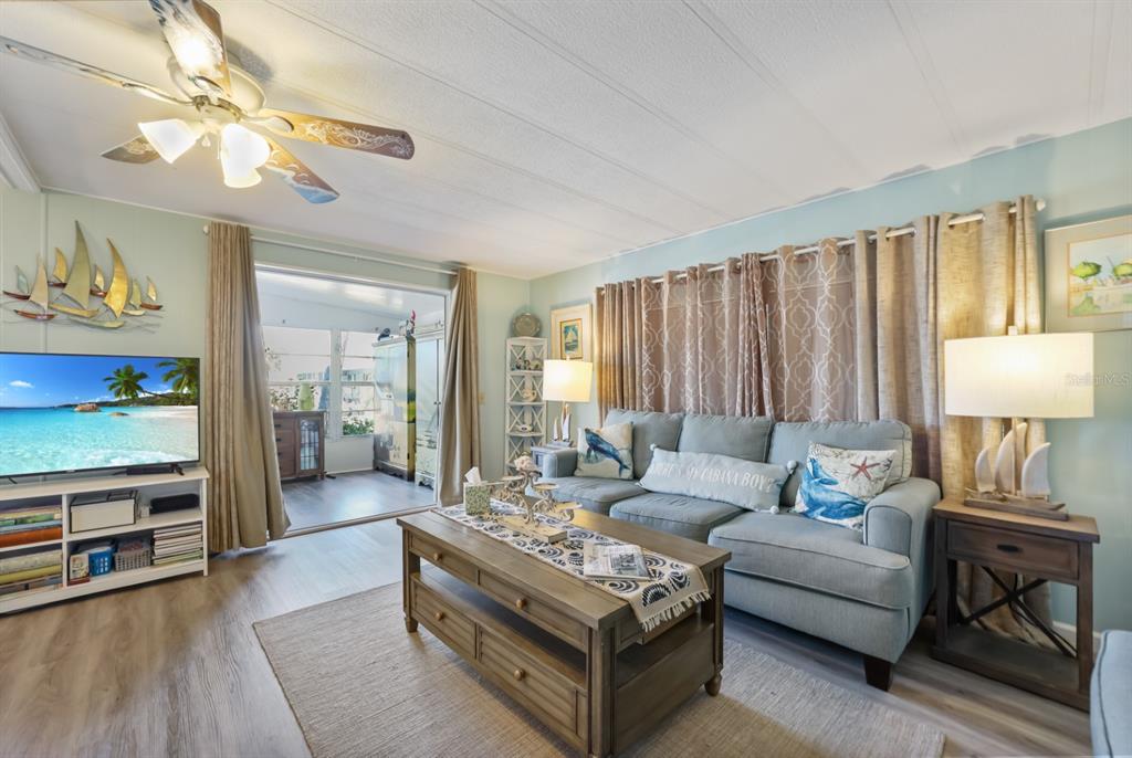 A living room features a blue sofa, a wooden coffee table, and a ceiling fan — 2100 KINGS HIGHWAY UNIT 59, PORT CHARLOTTE, FL