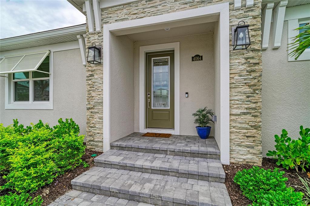 The front entrance features a green door, stone siding, and a brick-paved porch with steps — 4064 SANTA CATERINA BOULEVARD UNIT 101, LAKEWOOD RANCH, FL